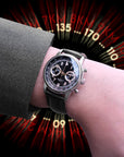 Hand wearing a wristwatch with a dynamic background featuring numbers and letters. Wearing Wancher Tenji Chronograph Watch