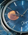 Close-up of a watch with a blue raden dial face and 'Kaguya' branding.\ and gold moon disk : Wancher raden dial watch featuring Kaguya-inspired moonphase display