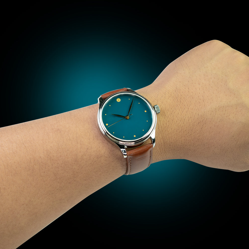 Wrist wearing a watch with a blue face and brown leather strap against a gradient background