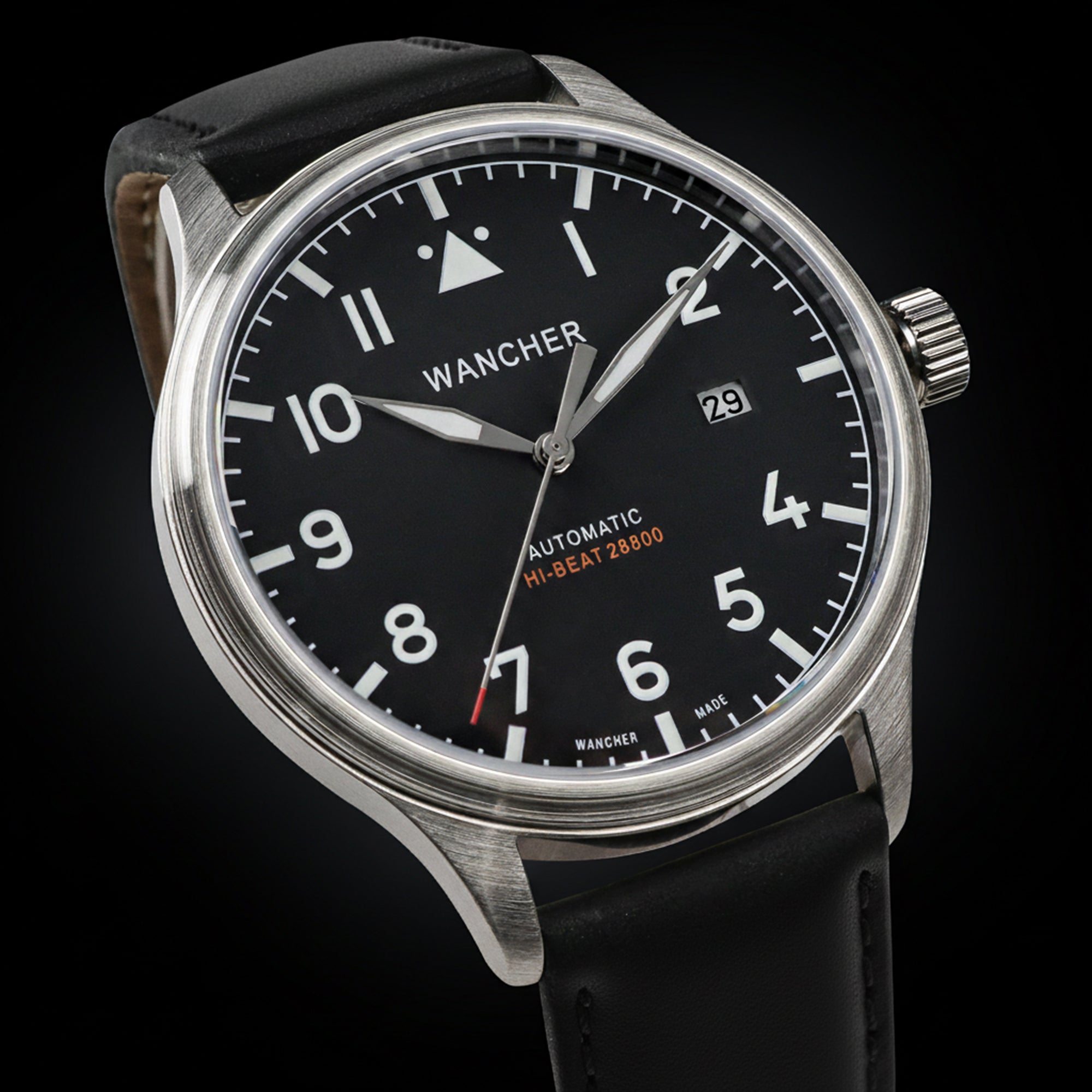 An automatic pilot watch from Wancher, the Flugel, with a Miyota 9015 movement, clearly visible on a wrist. The watch has a black dial and a brown strap.